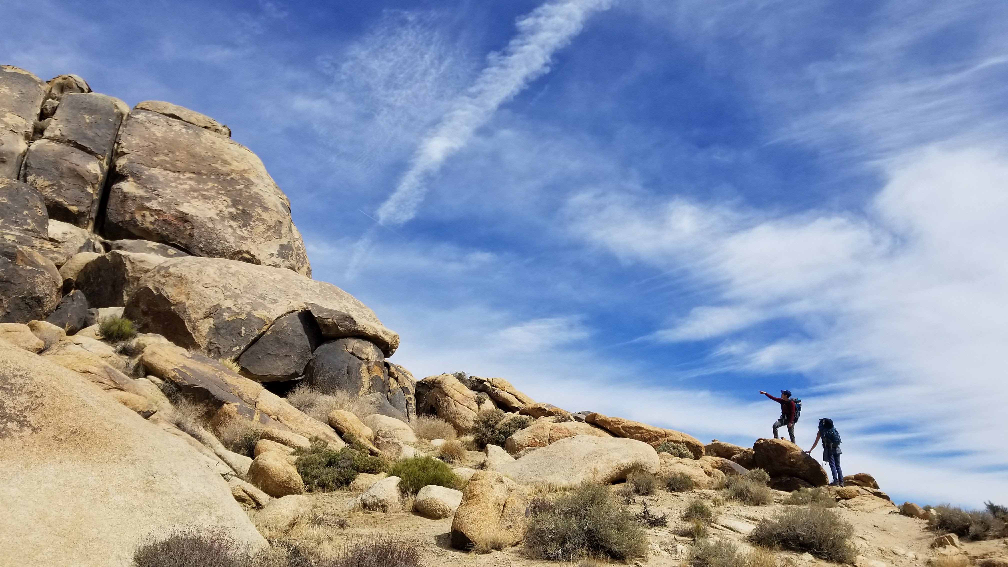 Two hikers on a rocky ridge against an open blue sky
